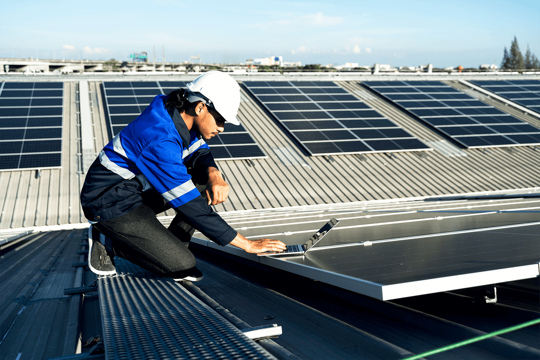 Ingegnere su tetto che monitora i pannelli fotovoltaici da portatile. incentivo fotovoltaico alle imprese
